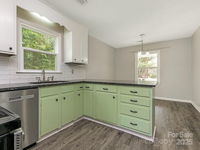 kitchen featuring plenty of natural light, dark wood-type flooring, a peninsula, green cabinets, and a sink