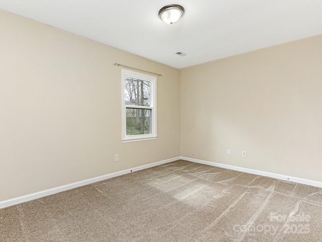 unfurnished room with carpet, visible vents, and baseboards