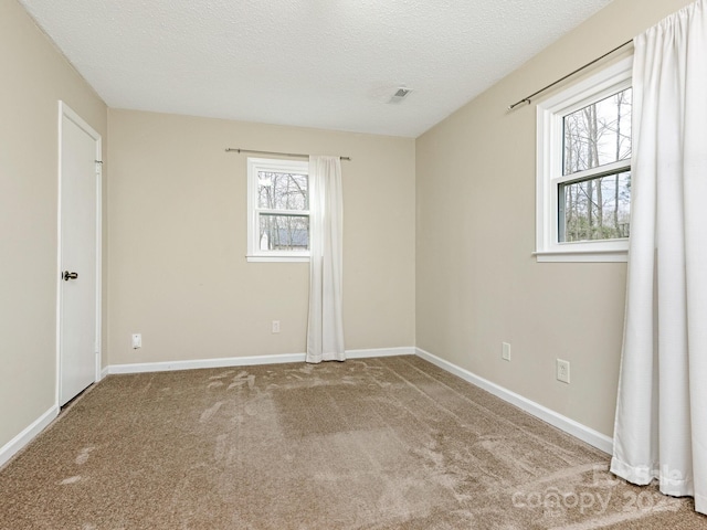 unfurnished room featuring a textured ceiling, carpet floors, visible vents, and baseboards