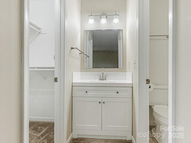 bathroom featuring vanity, toilet, and a spacious closet