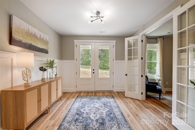 doorway featuring a wainscoted wall, light wood finished floors, and french doors