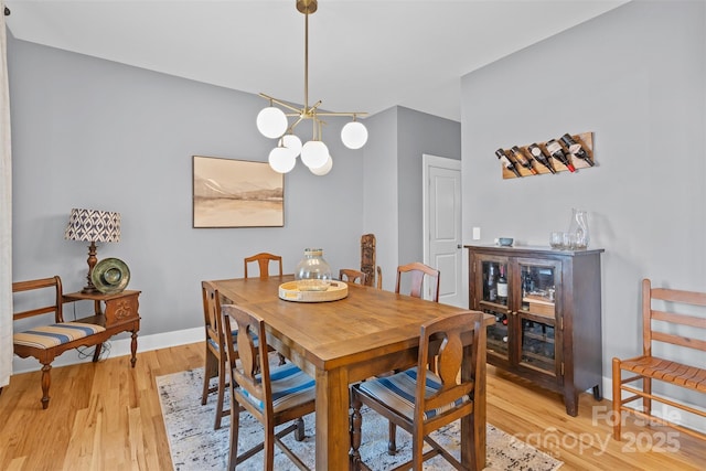 dining space featuring a notable chandelier, light wood-style floors, and baseboards