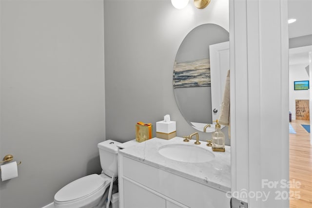 bathroom featuring toilet, wood finished floors, and vanity