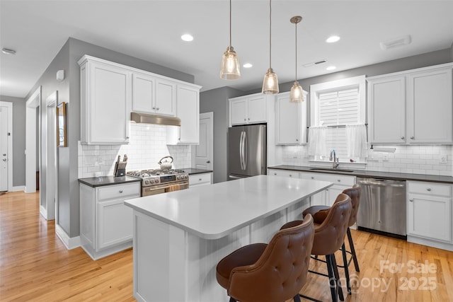 kitchen featuring a kitchen island, stainless steel appliances, light wood-style floors, and a sink