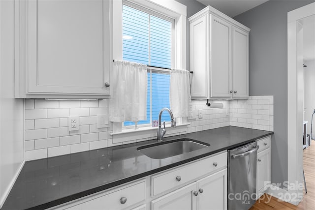 kitchen featuring a sink, dark countertops, dishwasher, and white cabinets