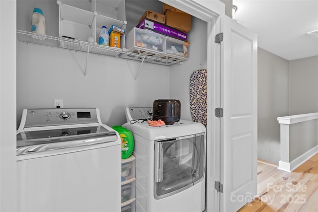 clothes washing area featuring washer and dryer, laundry area, baseboards, and light wood finished floors