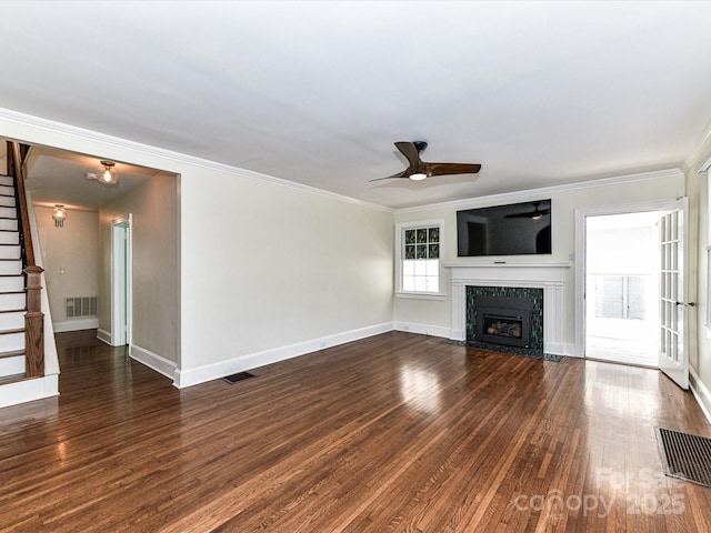 unfurnished living room featuring a high end fireplace, visible vents, dark wood finished floors, and stairs