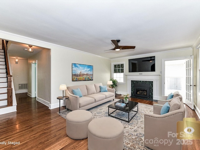 living area with stairway, wood finished floors, visible vents, a high end fireplace, and ornamental molding