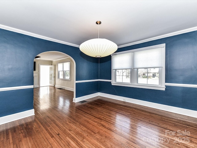 spare room featuring visible vents, baseboards, arched walkways, ornamental molding, and wood-type flooring