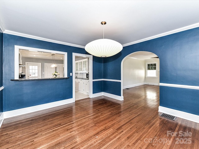 unfurnished room with visible vents, ornamental molding, baseboards, and wood finished floors