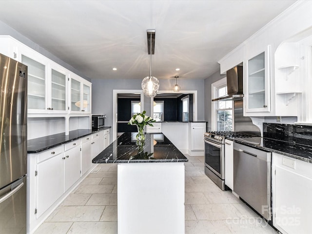 kitchen featuring white cabinetry, dark stone counters, appliances with stainless steel finishes, and a center island