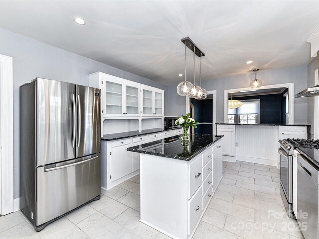 kitchen with a center island, glass insert cabinets, dark stone counters, white cabinets, and stainless steel appliances