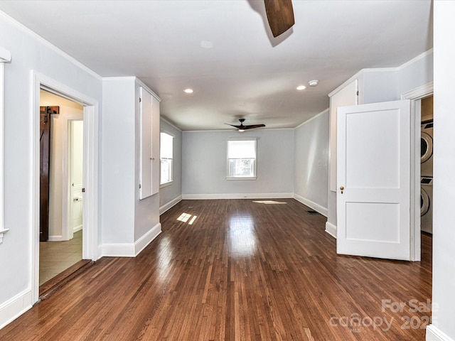 spare room with dark wood finished floors, crown molding, stacked washer and dryer, and ceiling fan