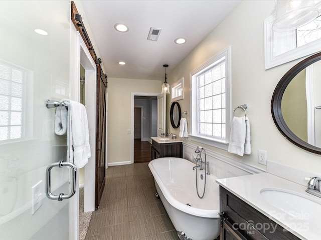 full bath featuring a sink, visible vents, a freestanding bath, and recessed lighting