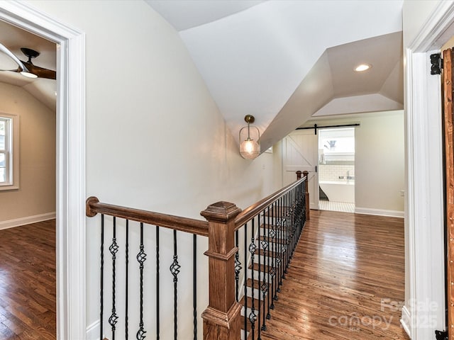 staircase with baseboards, lofted ceiling, a barn door, and wood finished floors