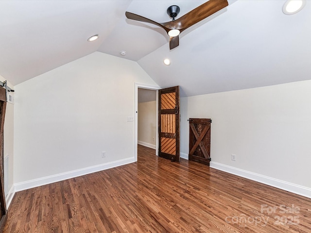 bonus room with ceiling fan, baseboards, lofted ceiling, a barn door, and wood finished floors