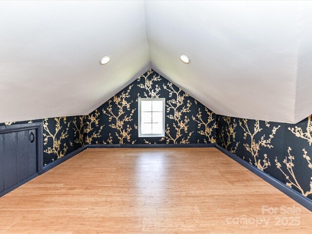 additional living space featuring wallpapered walls, lofted ceiling, recessed lighting, and wood finished floors