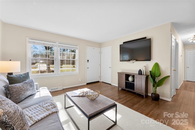 living area featuring visible vents, wood finished floors, and baseboards