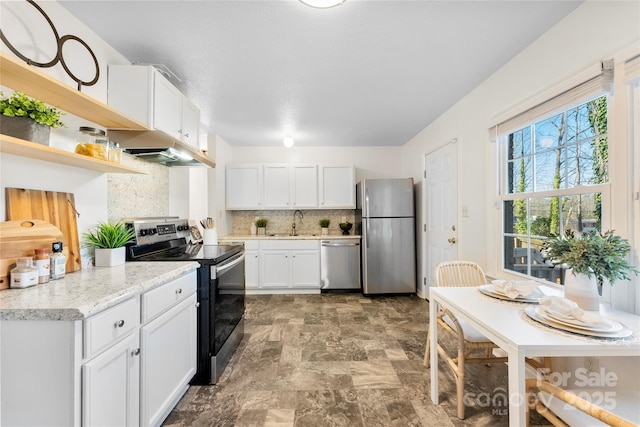 kitchen with a sink, decorative backsplash, stainless steel appliances, white cabinetry, and open shelves