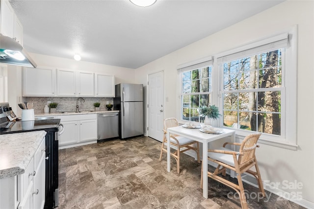 kitchen featuring a sink, stainless steel appliances, under cabinet range hood, white cabinetry, and tasteful backsplash