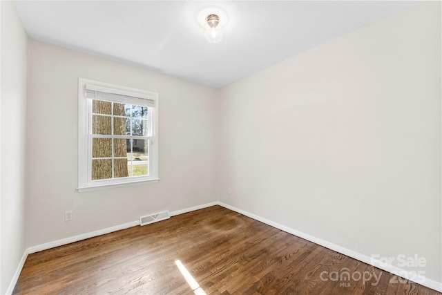 unfurnished room featuring visible vents, baseboards, and wood finished floors