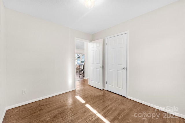 unfurnished bedroom featuring wood finished floors and baseboards