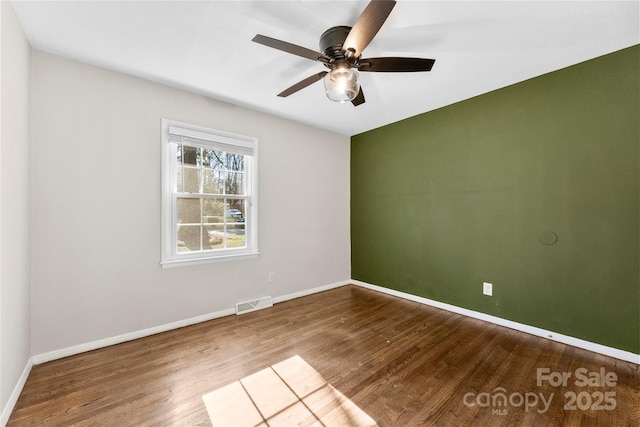 empty room featuring visible vents, ceiling fan, baseboards, and wood finished floors