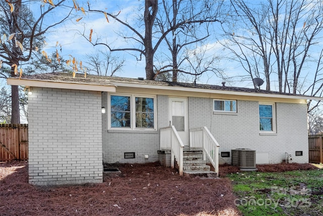 back of property featuring crawl space, central air condition unit, brick siding, and fence