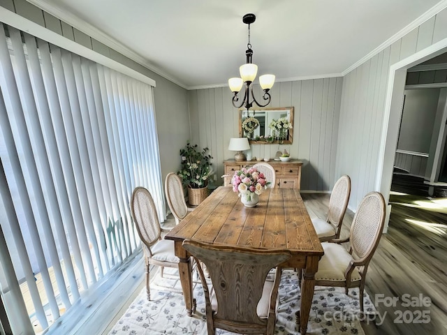 dining room with a chandelier, crown molding, and wood finished floors