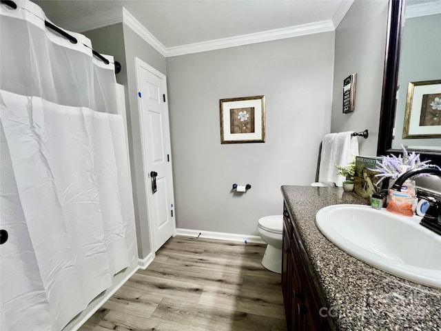 bathroom featuring toilet, ornamental molding, vanity, wood finished floors, and baseboards