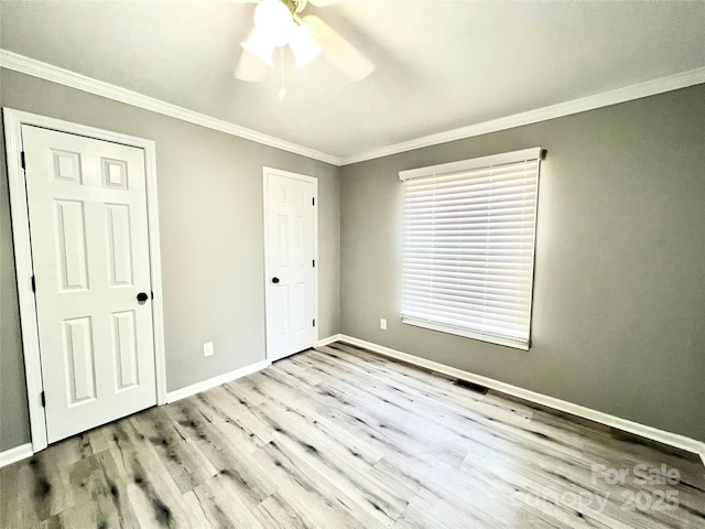 unfurnished bedroom with ornamental molding, visible vents, baseboards, and wood finished floors