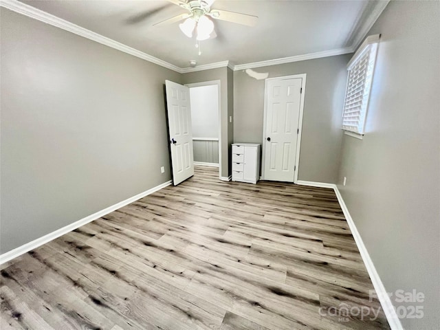 unfurnished bedroom with a ceiling fan, baseboards, crown molding, and wood finished floors