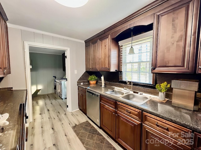 kitchen featuring crown molding, dark countertops, light wood-style flooring, appliances with stainless steel finishes, and a sink