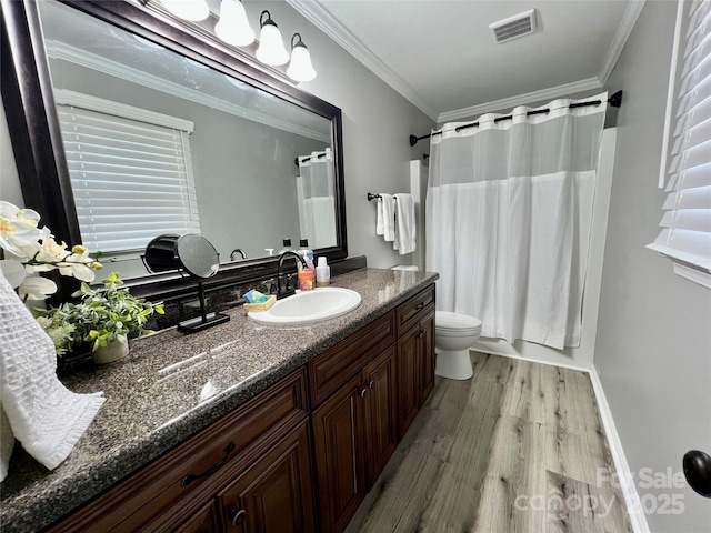 bathroom featuring visible vents, toilet, wood finished floors, crown molding, and vanity