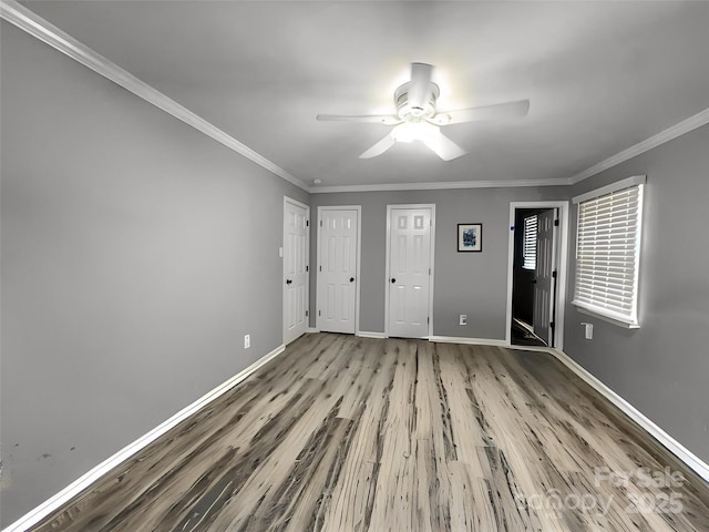 empty room featuring ornamental molding, ceiling fan, baseboards, and wood finished floors