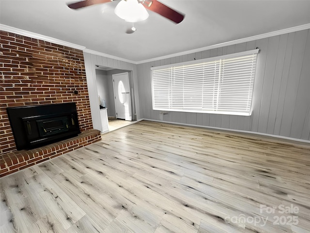 unfurnished living room featuring a brick fireplace, a ceiling fan, crown molding, and wood finished floors