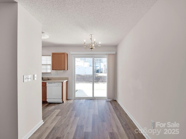 unfurnished dining area featuring baseboards, wood finished floors, a textured ceiling, and a chandelier