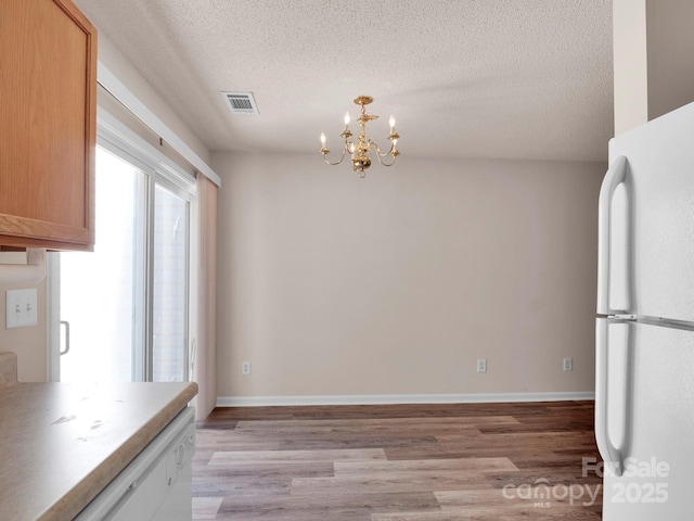 kitchen with visible vents, a textured ceiling, freestanding refrigerator, and light wood-style floors