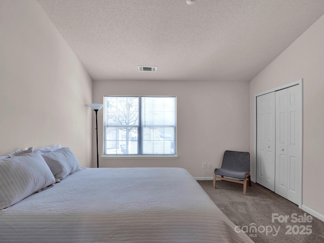 carpeted bedroom featuring visible vents, baseboards, a textured ceiling, and a closet