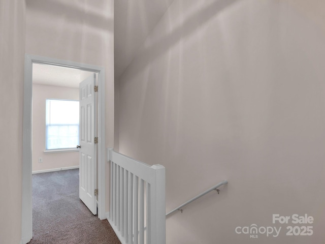 corridor featuring baseboards, an upstairs landing, and carpet flooring