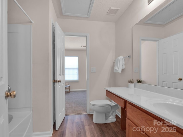 full bathroom with visible vents, toilet, vanity, wood finished floors, and a textured ceiling