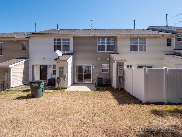 rear view of house featuring cooling unit, a lawn, and fence