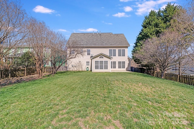 back of house with a fenced backyard and a lawn