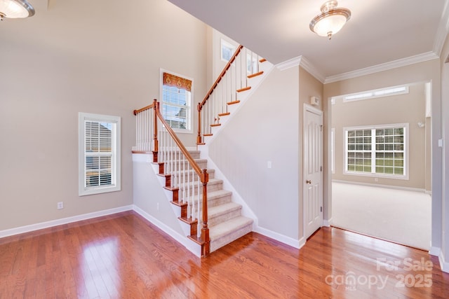 stairway with ornamental molding, baseboards, and hardwood / wood-style flooring