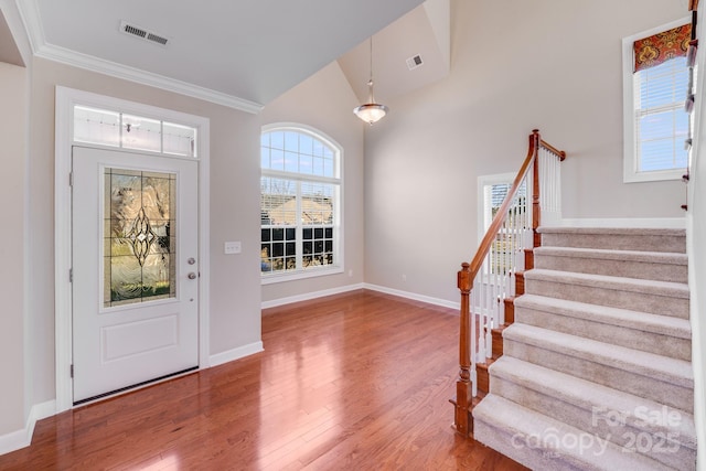 entryway with stairway, baseboards, visible vents, and wood finished floors