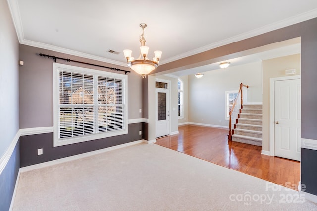 empty room with crown molding, a notable chandelier, visible vents, stairway, and wood finished floors