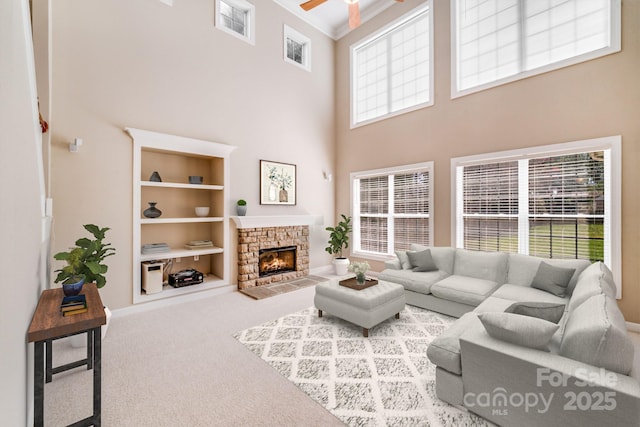 living room featuring carpet, a fireplace, visible vents, ornamental molding, and ceiling fan