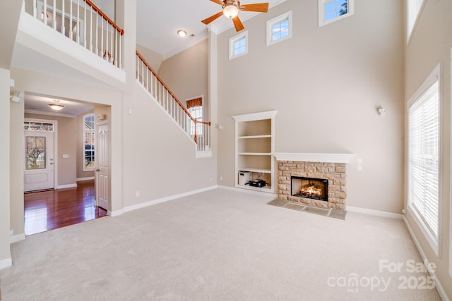 unfurnished living room with carpet floors, a wealth of natural light, ornamental molding, and a towering ceiling