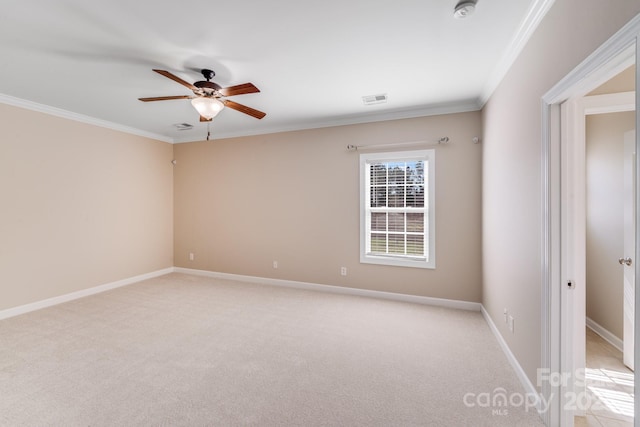 spare room with light colored carpet, visible vents, crown molding, and baseboards