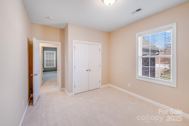 unfurnished bedroom featuring light colored carpet, visible vents, and baseboards